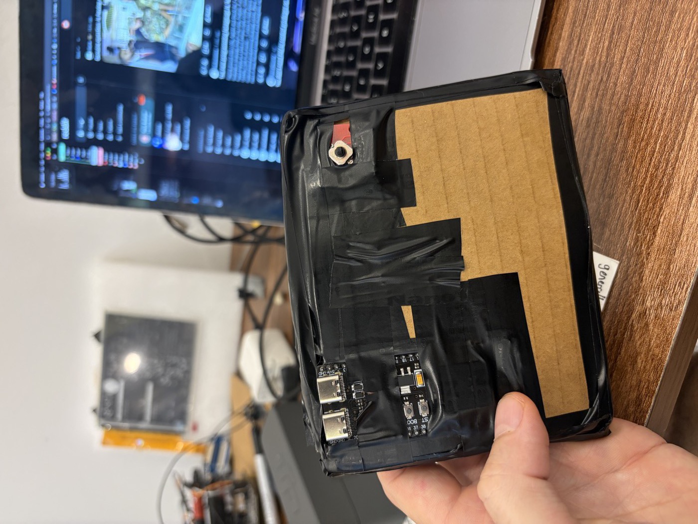 Back of the reader showing the dev board's two USB-C ports and the five-way button poking through black tape and cardboard.
