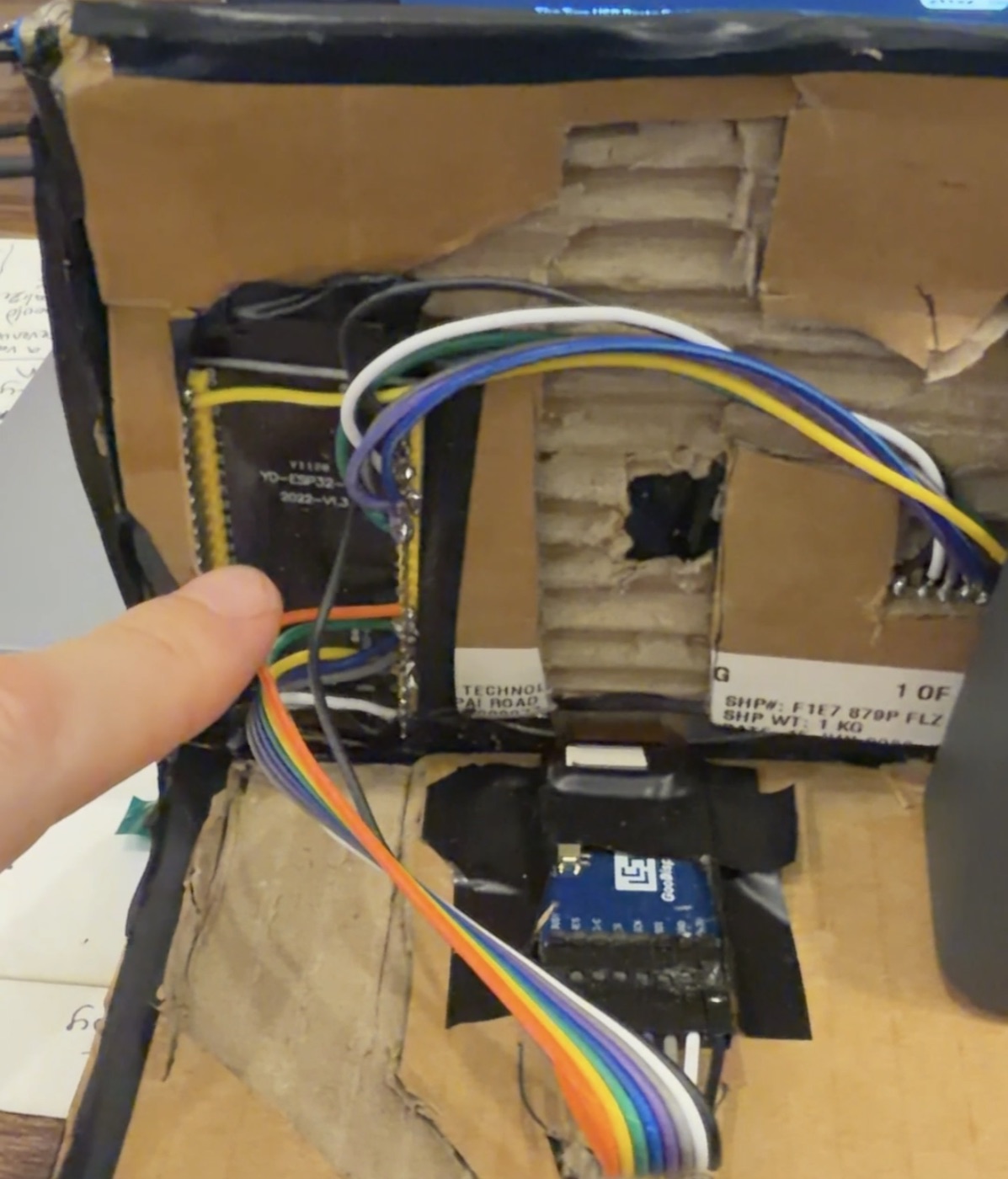 Inside the case: an ESP32-S3 dev board with soldered wires running to a blue Good Display adapter board taped to cardboard.